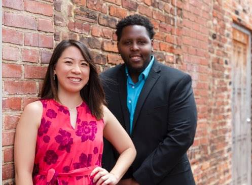 woman and a man standing near a brick wall